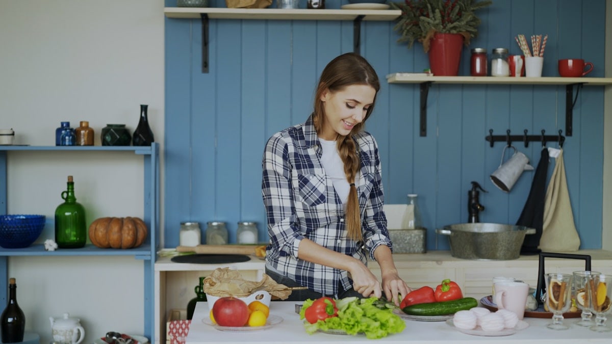 Cheerful young woman cooking breakfast in the kitchen early morning at home