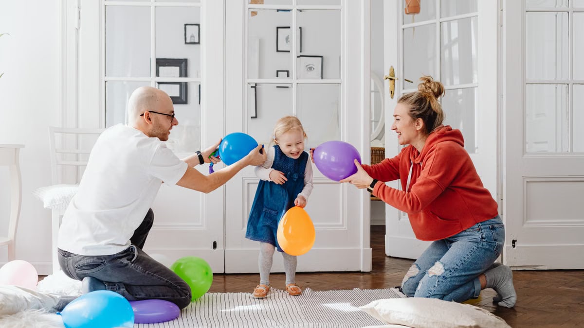 A joyful family playing with colorful balloons indoors, capturing a fun bonding moment.